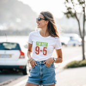 Woman wearing a white t-shirt with 'I'm Not 9-5' text, standing outdoors.