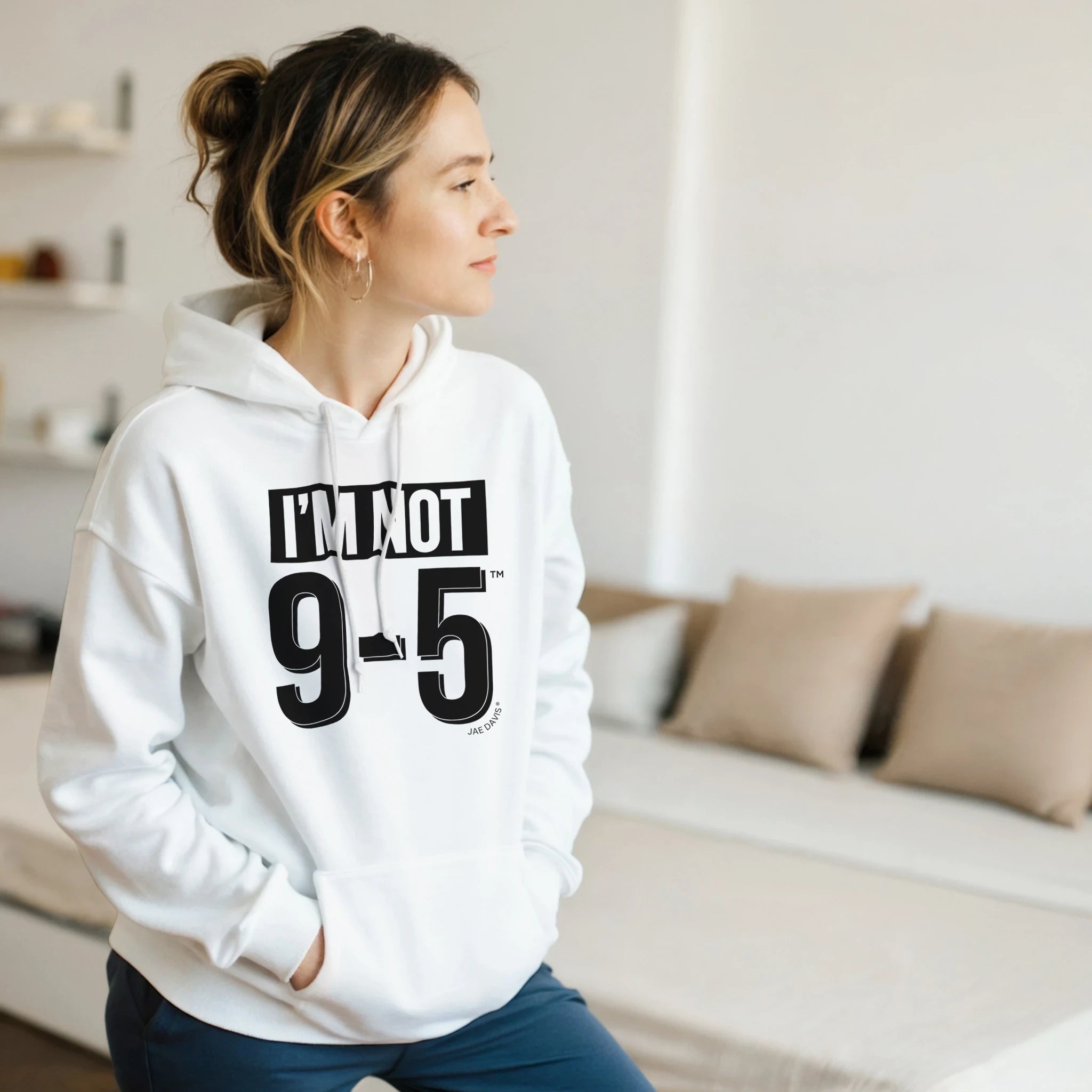 Person wearing a white hoodie with text in a living room