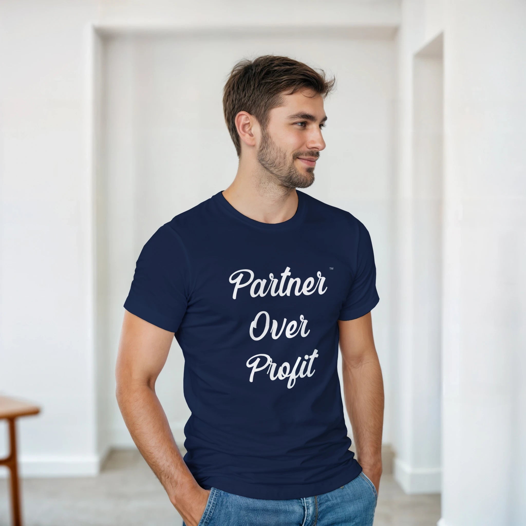 Man wearing a navy blue t-shirt with 'Partner Over Profit' text in a minimal indoor setting