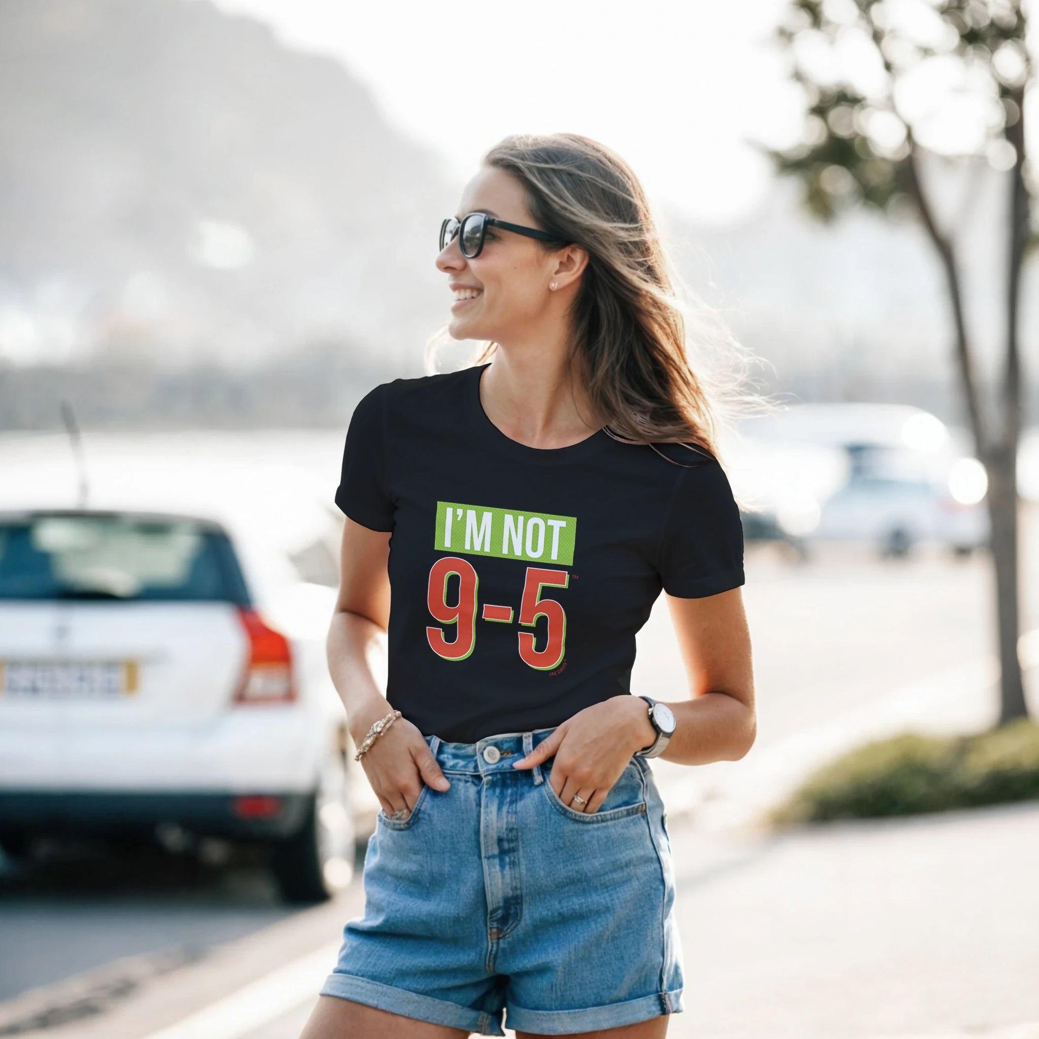 Woman wearing a black t-shirt with 'I'm Not 9-5' text, standing outdoors.