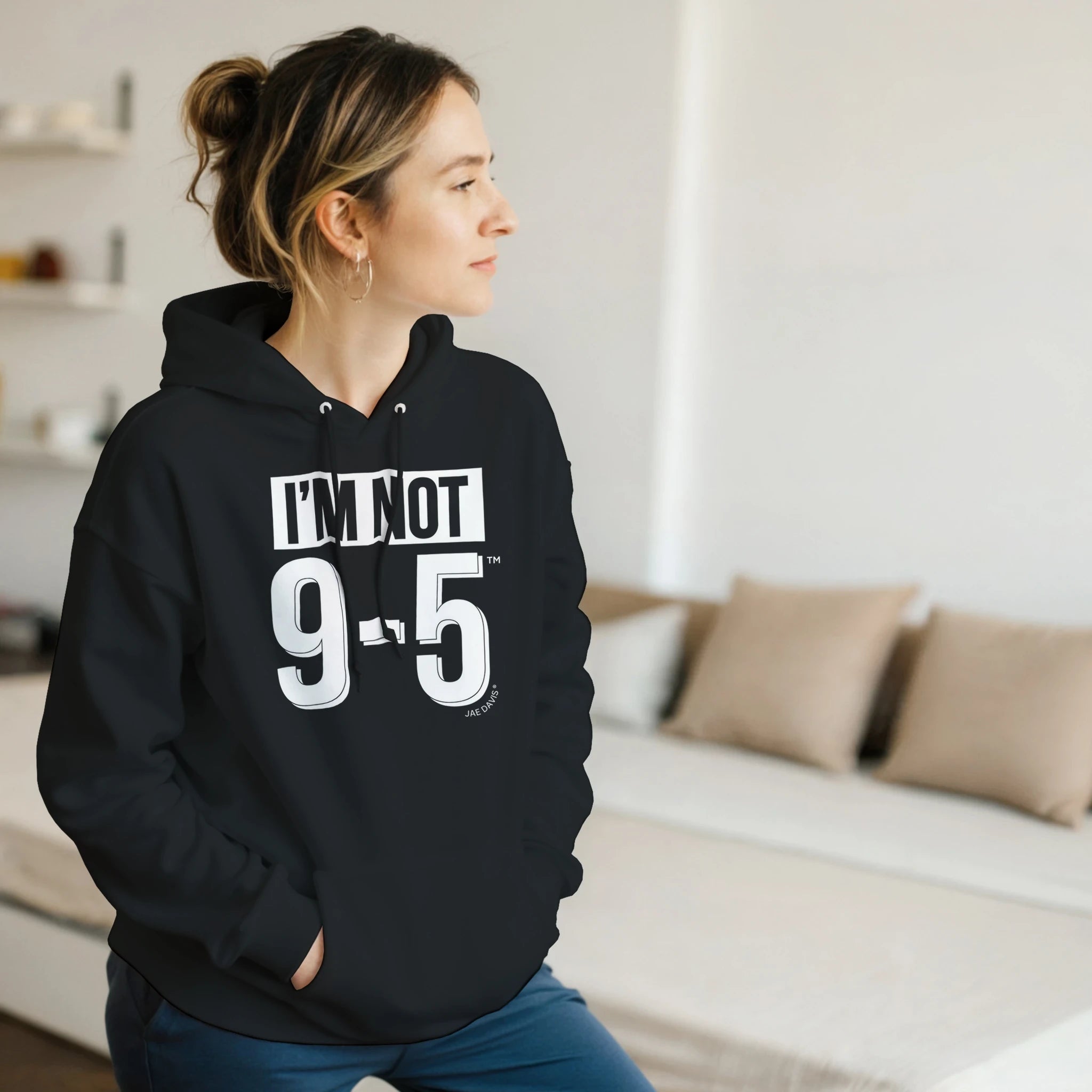 Person wearing a black hoodie with text in a living room