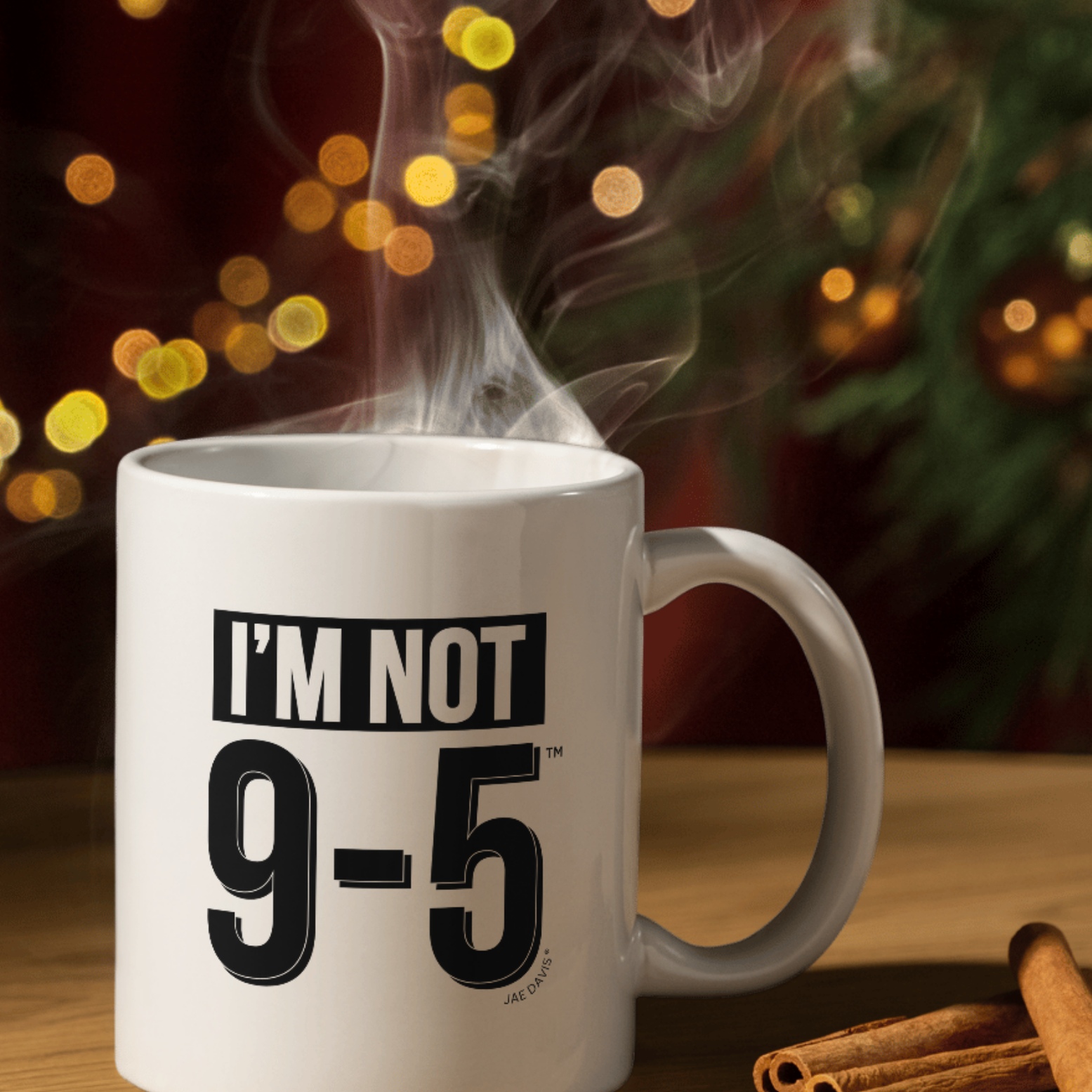 White mug with 'I'm Not 9-5' text on a wooden surface with cinnamon sticks, against a blurred festive background.