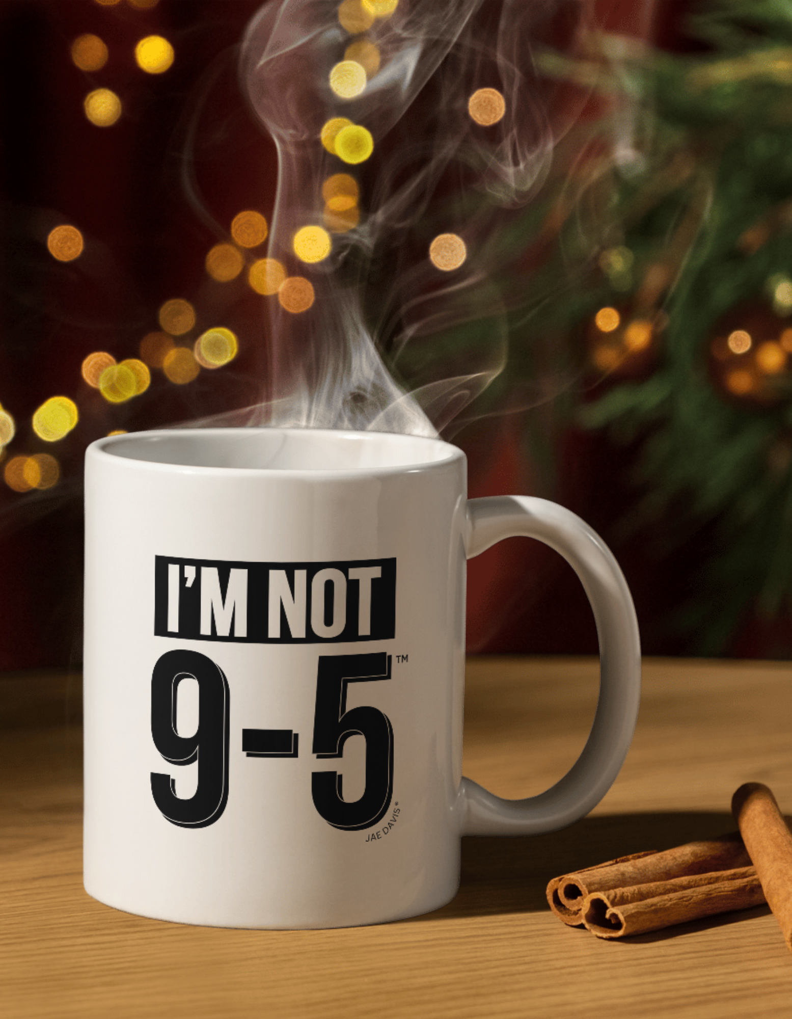 White mug with 'I'm Not 9-5' text on a wooden surface with cinnamon sticks, against a blurred festive background.