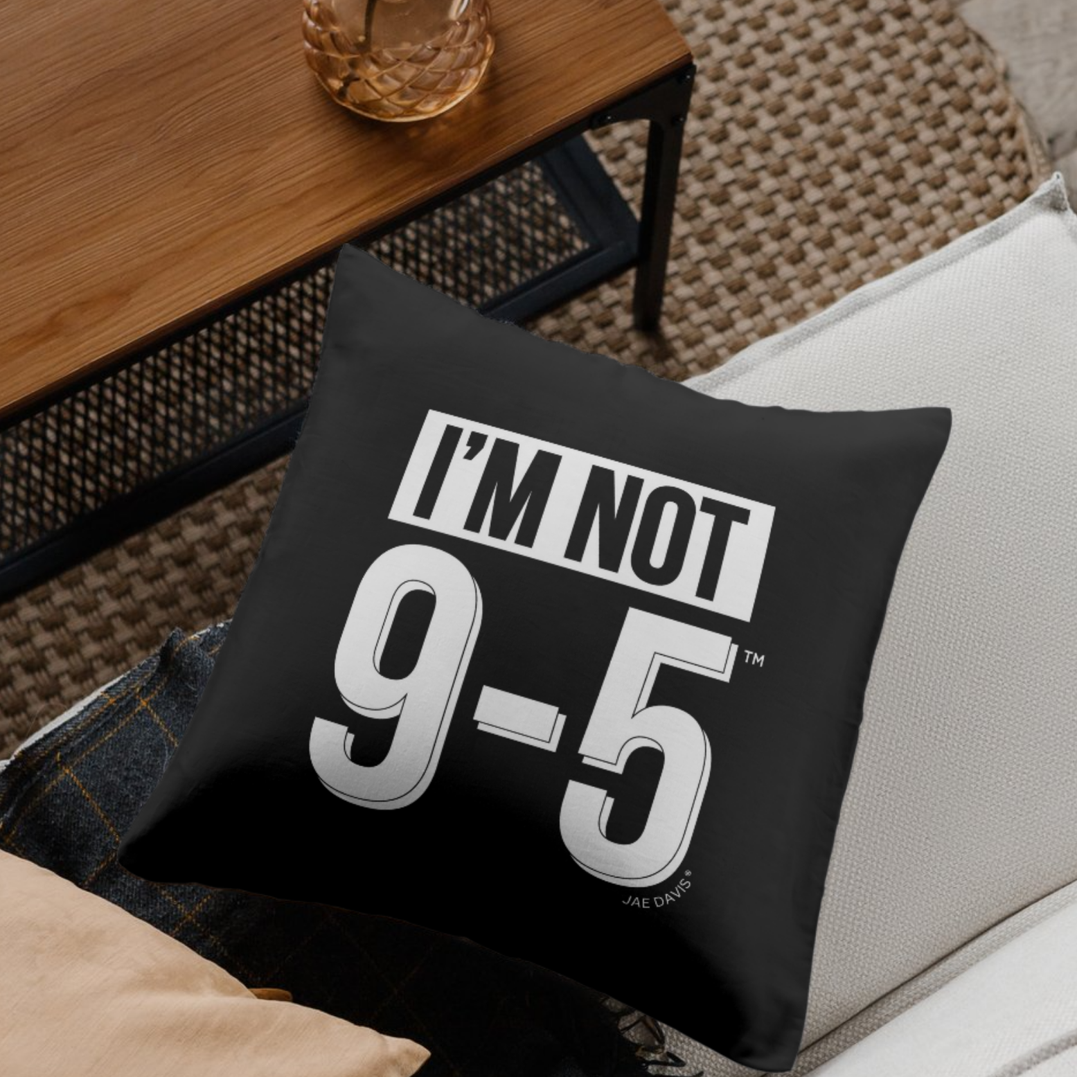 Black pillow with 'I'm Not 9-5' text on a couch in a living room setting.