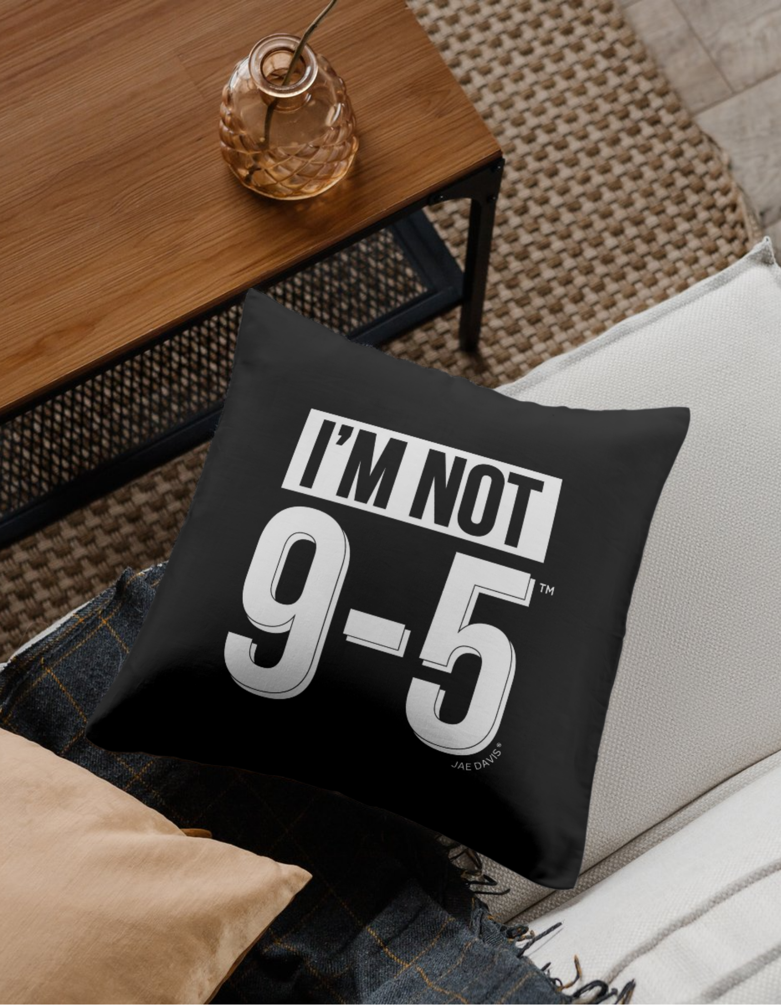 Black pillow with 'I'm Not 9-5' text on a couch in a living room setting.