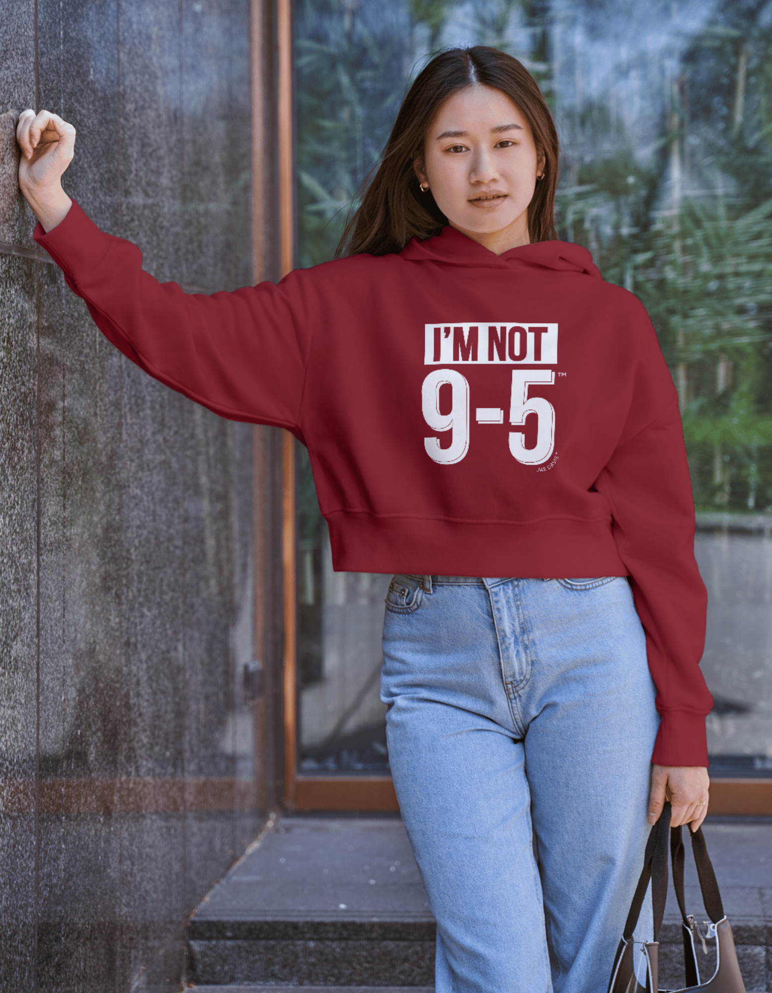 Person wearing a red hoodie with 'I'm Not 9-5' text, standing outdoors.