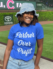 Person wearing a blue shirt with 'Partner Over Profit' text at a sports event.