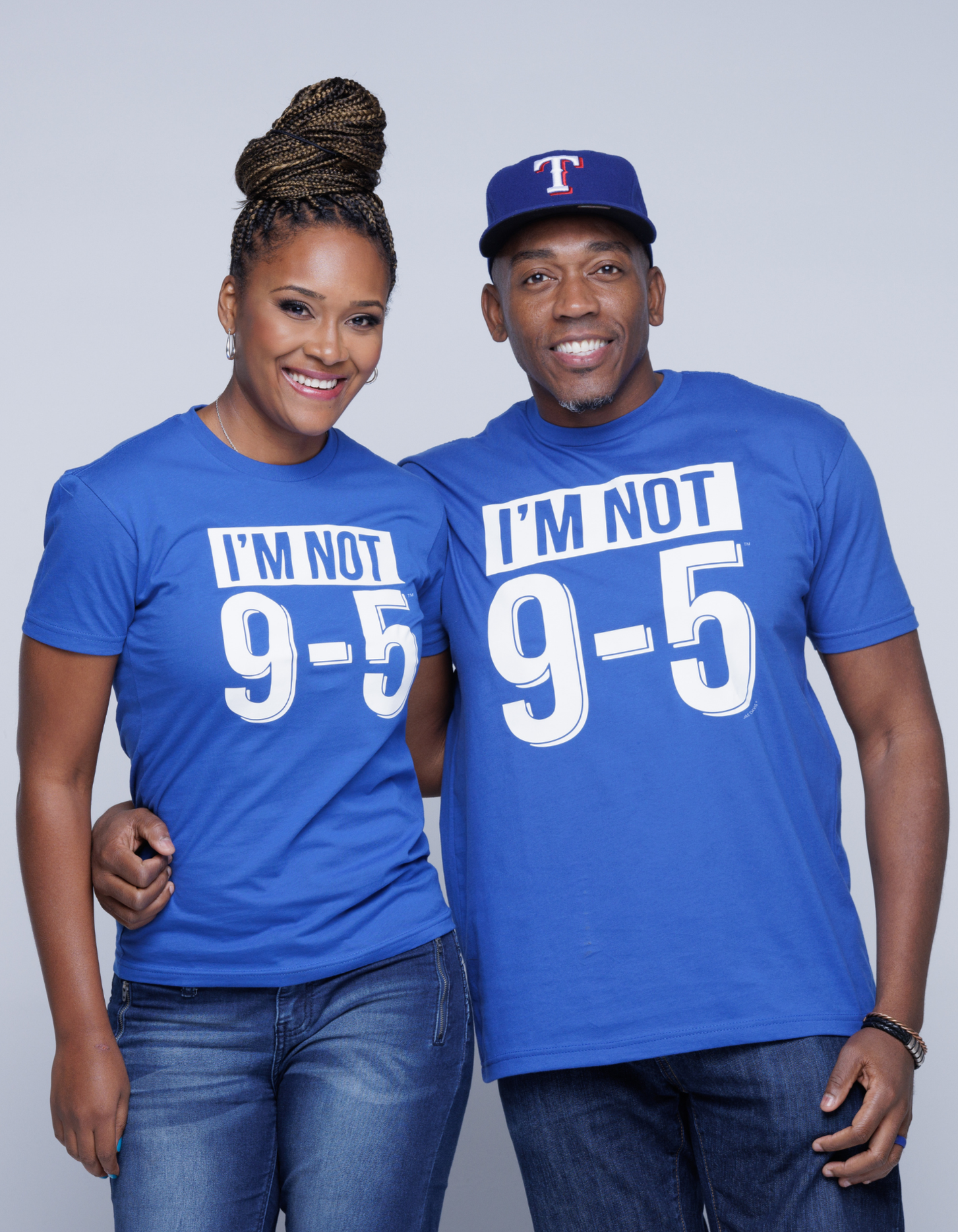 Two people wearing blue t-shirts with 'I'm Not 9-5' text on a plain background