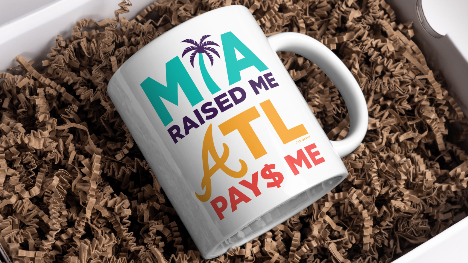 White mug with colorful text on a bed of brown shredded paper