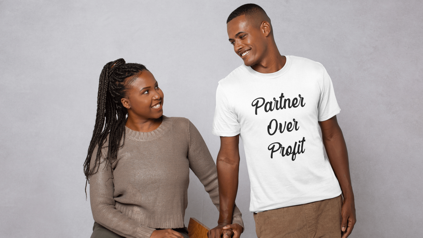 Man wearing a &#39;Partner Over Profit&#39; shirt standing next to a woman on a gray background