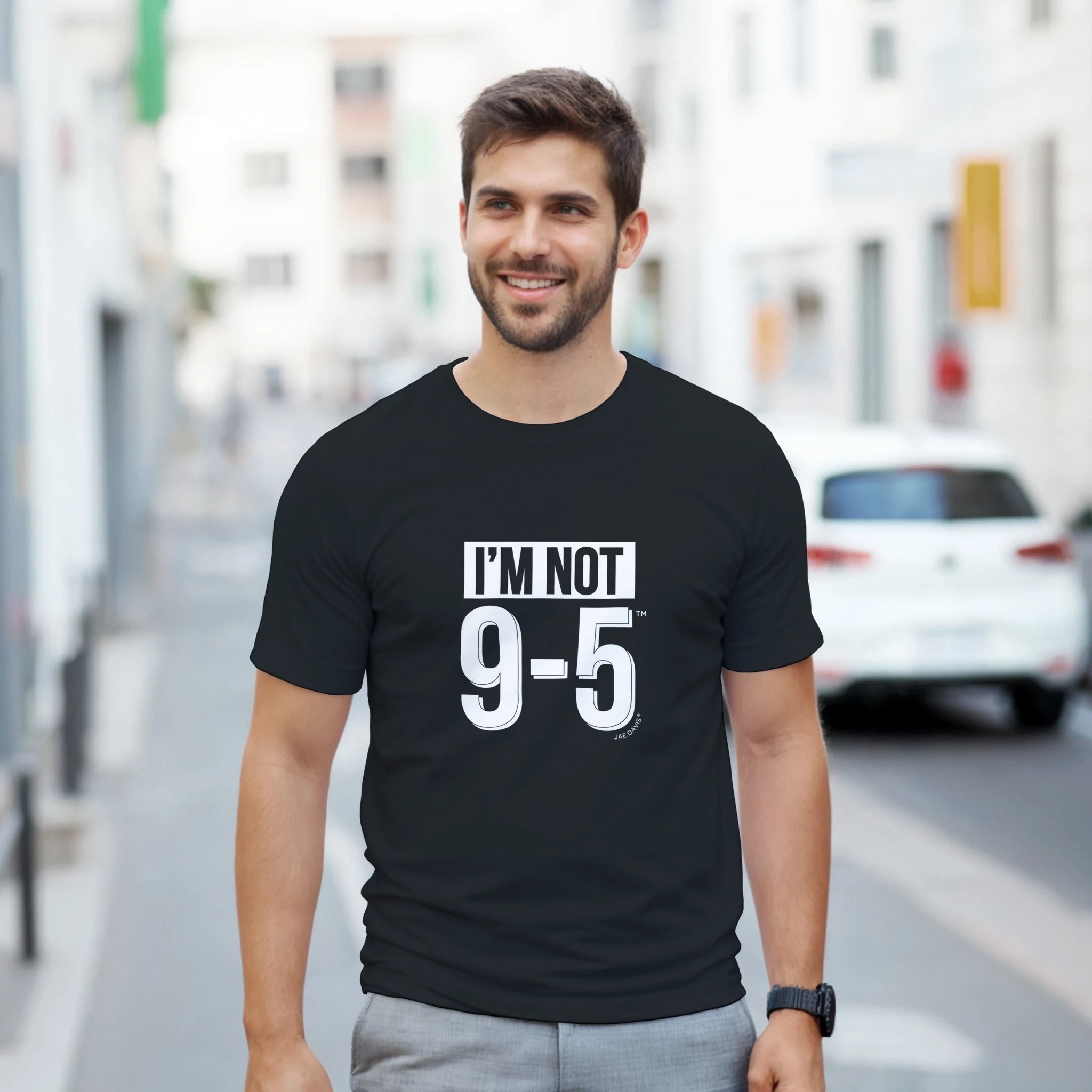 Man wearing a black t-shirt with 'I'M NOT 9-5' text on a city street.